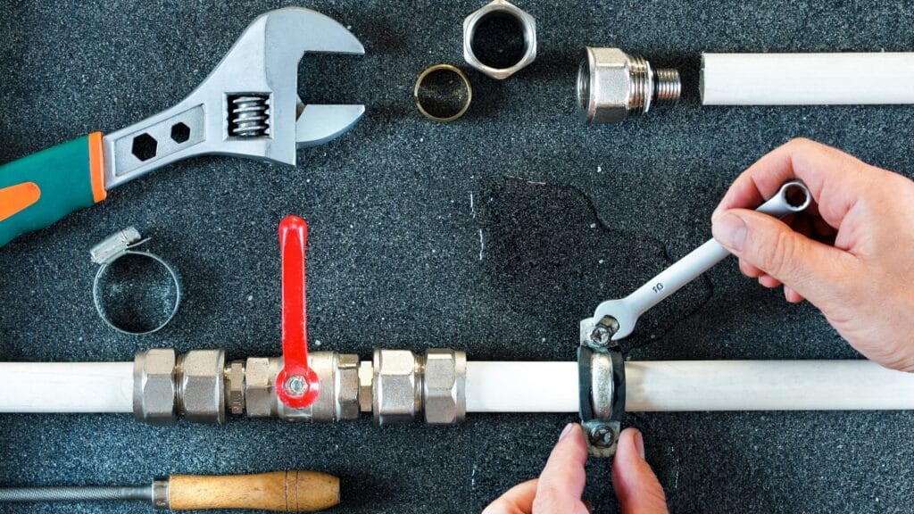 Plumber repairing a pipe valve with an adjustable wrench in Fort Walton Beach